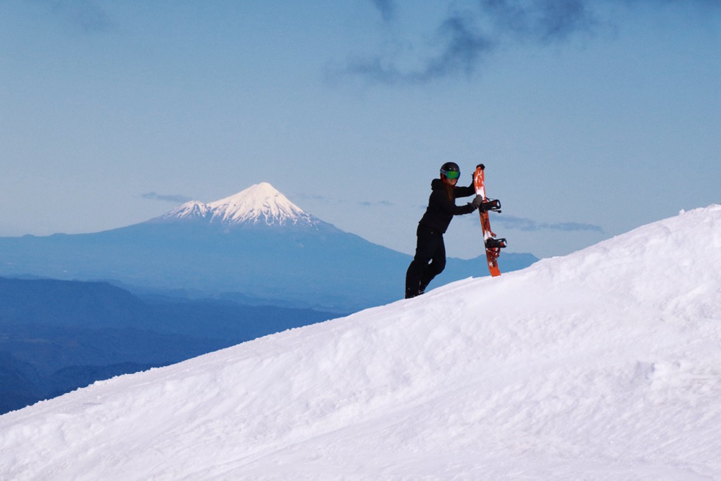 Mount Taranaki from Turoa Skifield, snowboarder in background, winter season, New Zealand