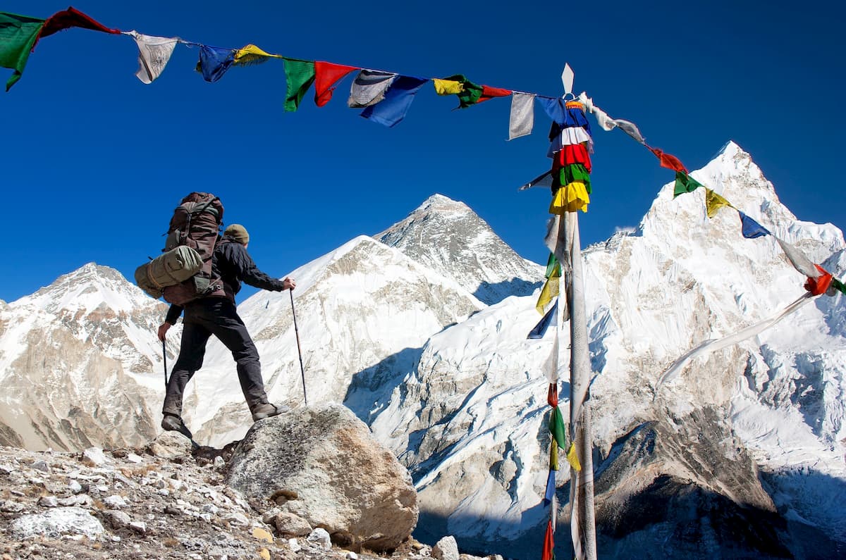 View of Everest with tourist and buddhist prayer flags from Kala Patthar and blue sky - way to Everest Base Camp