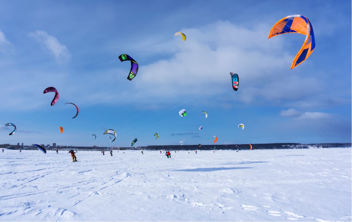 Snowkiters compete in a race on the ice of a frozen lake