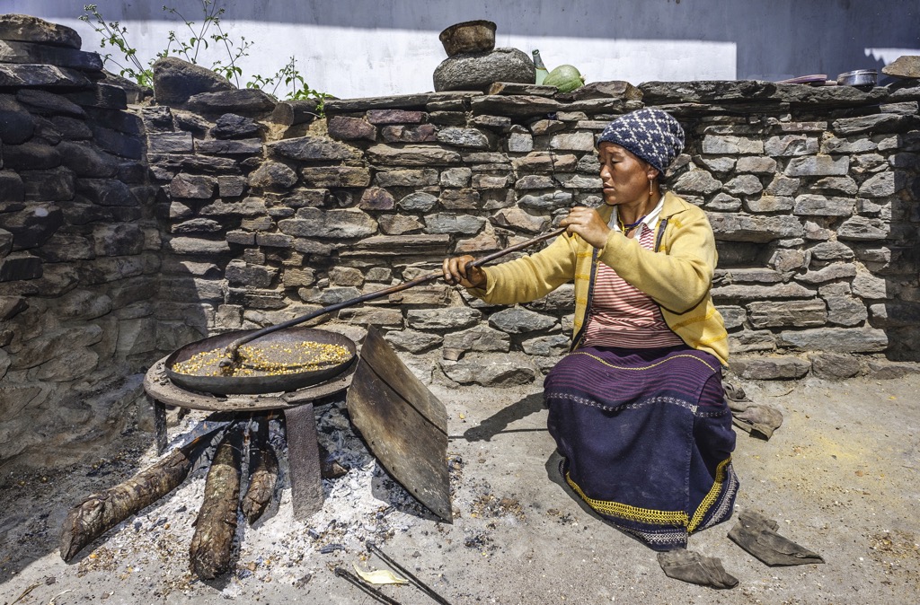 Arunachal Pradesh. Monpa woman roasts maize in the traditional way