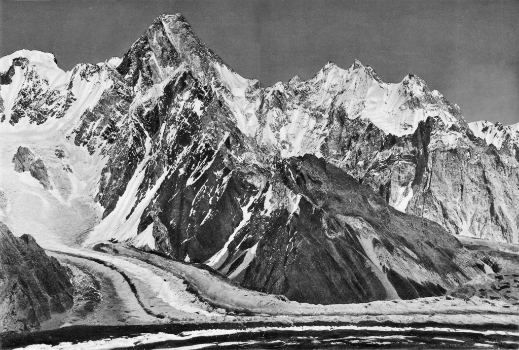 The Gasherbrum group rising above the striped moraines of the Baltoro Glacier, in a black-and-white photograph from 1909
