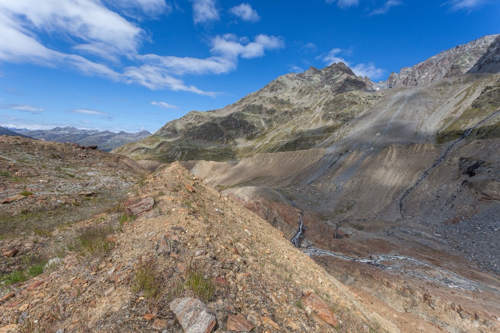 The towering moraines on the valley walls exhibit the most recent historical terminus of the Vallelunga Glacier, approximately 150 years ago. Planol Mountains