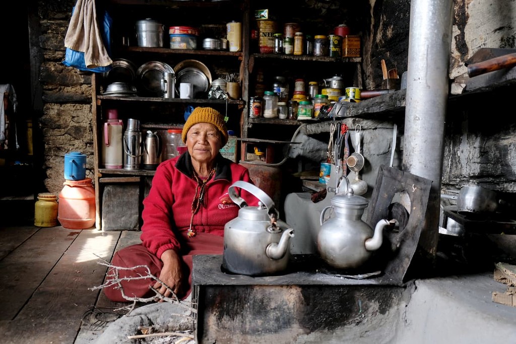 Buddhist monk (lama) sitting inside kitchen of Praken Gompa