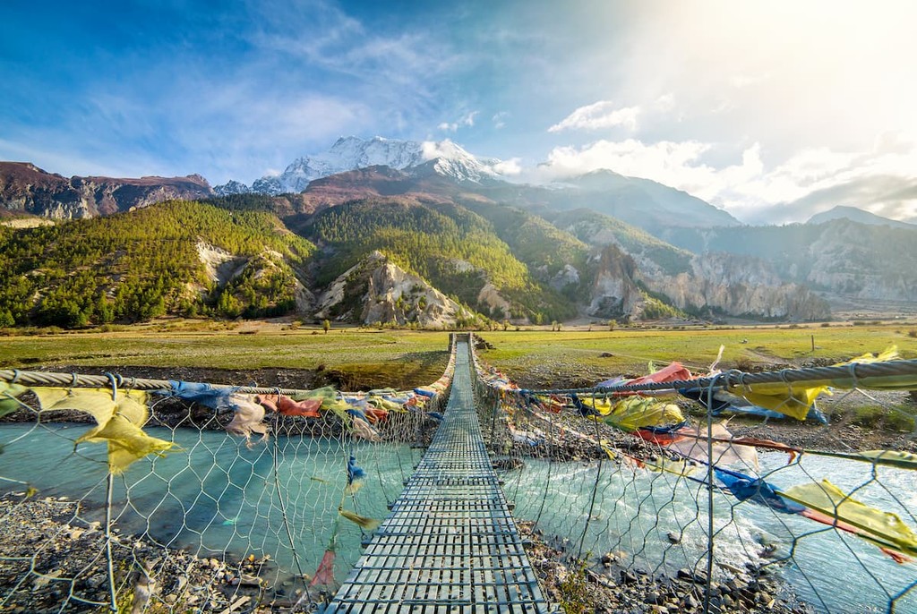 Suspension bridge with buddhist prayer flags on the Annapurna circuit trek in Nepal.