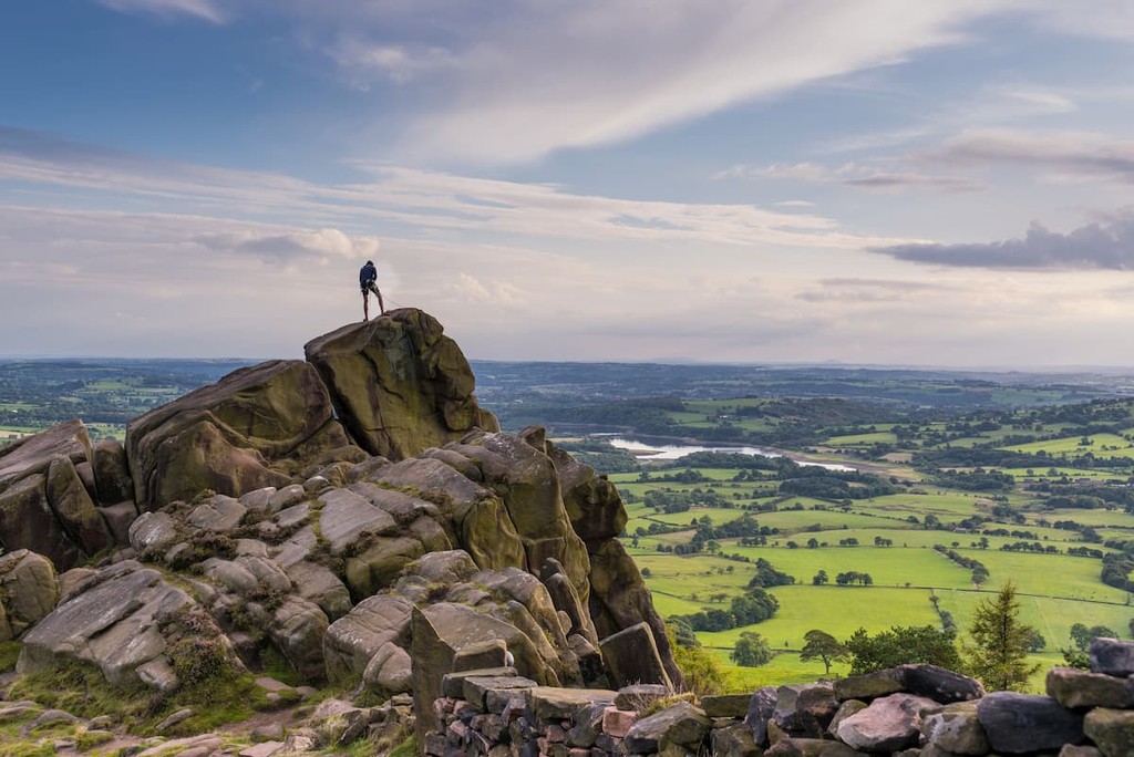 A climber at the roaches with a view over Tittisworth, Peak District National Park